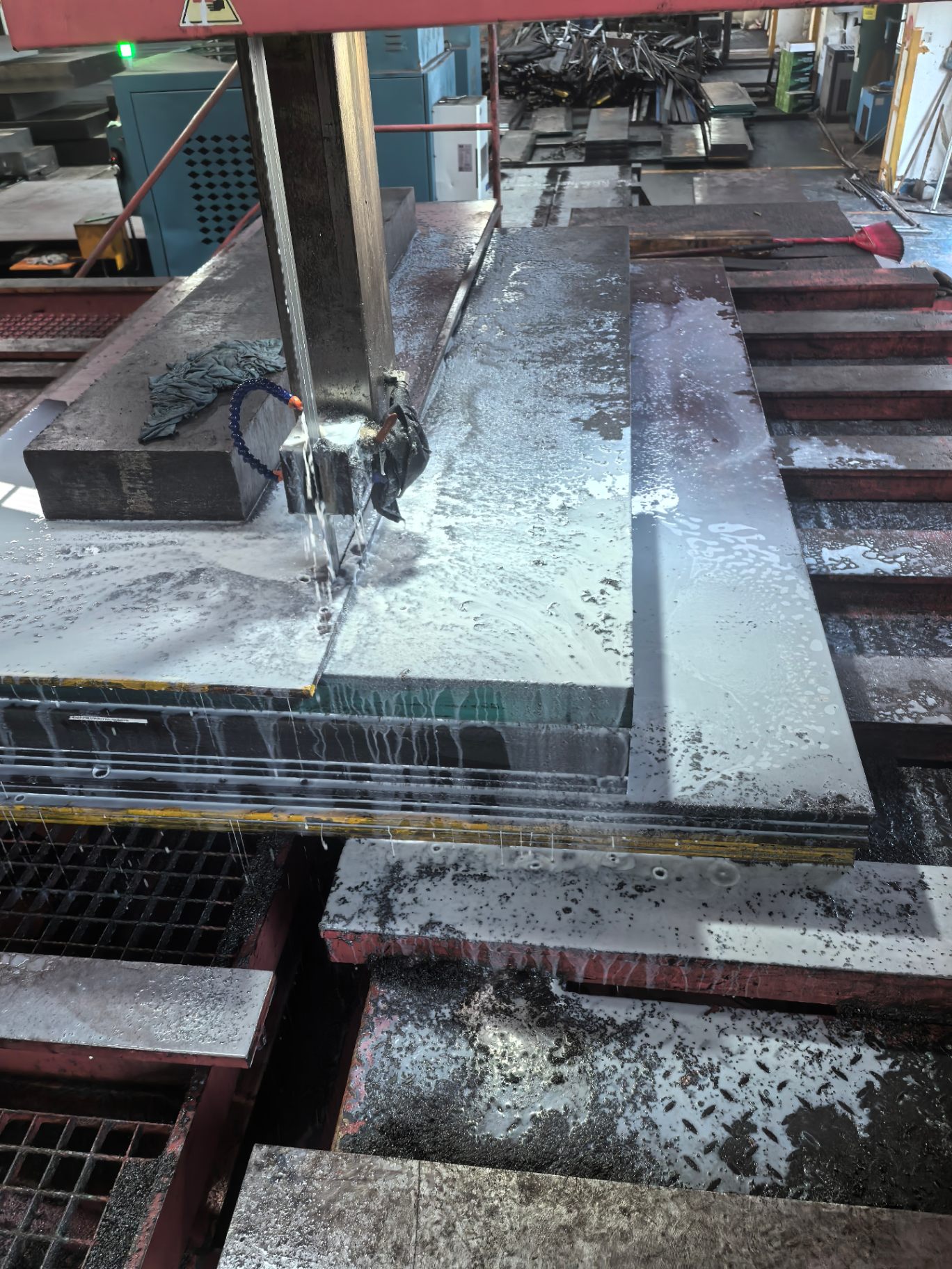 Band saw cutting steel plates to size with coolant